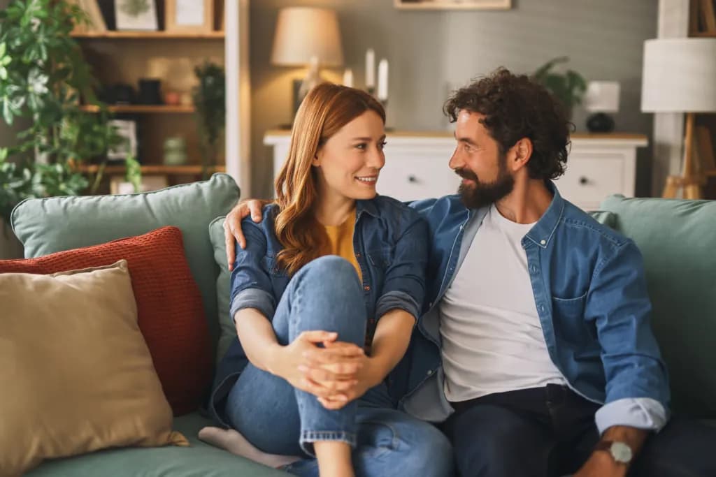 Smiling couple enjoying time together at home, sitting on a comfortable sofa, having a pleasant conversation